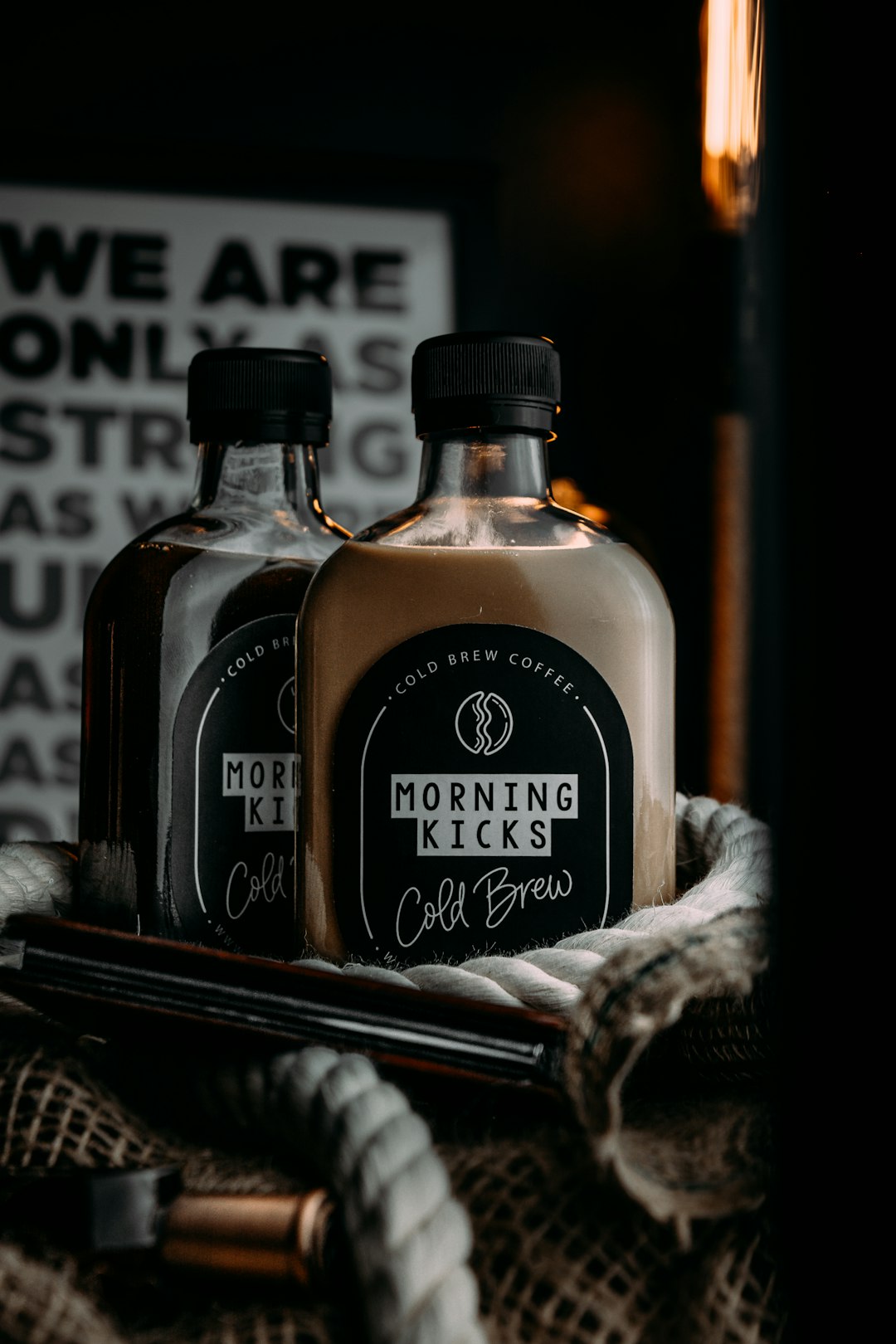 Glass bottles of cold brew coffee on old rusty table with thick rope and decoration