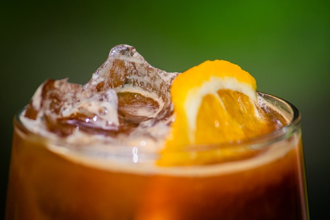 Close-up of a refreshing iced tea with an orange slice and ice cubes.